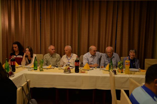 A group of people sitting at a table in front of a curtain

Description generated with very high confidence