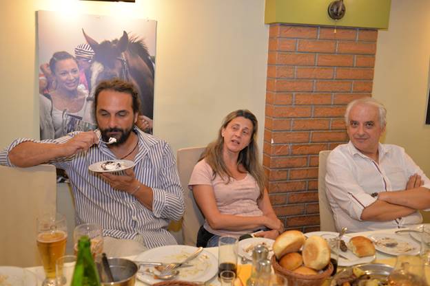 A group of people sitting at a table with food

Description generated with very high confidence