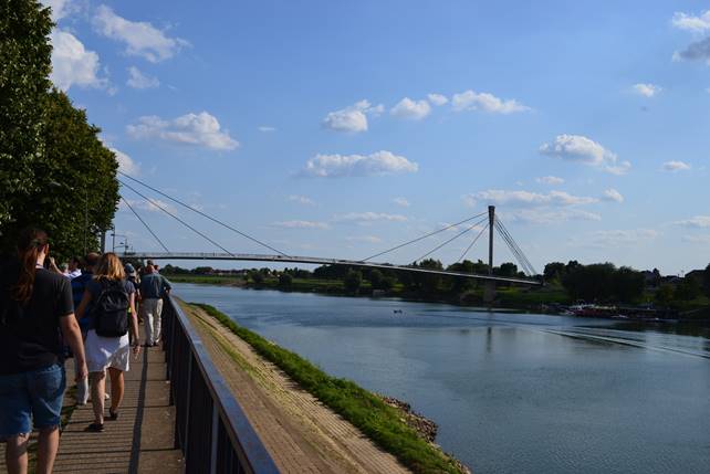 A group of people crossing a bridge over a body of water

Description generated with very high confidence