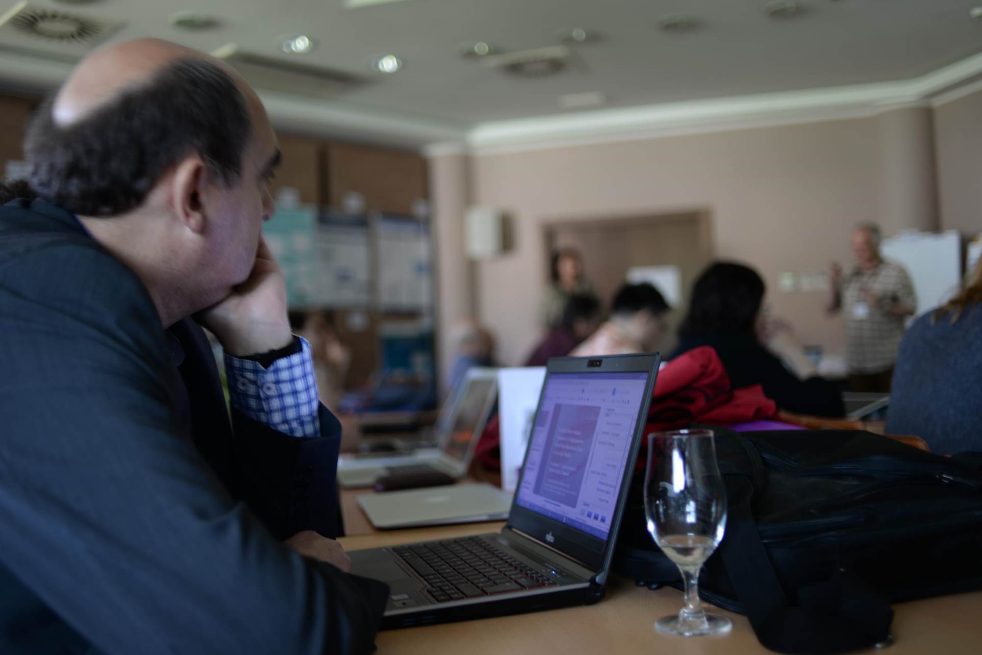 A group of people sitting at a table using a computer

Description automatically generated