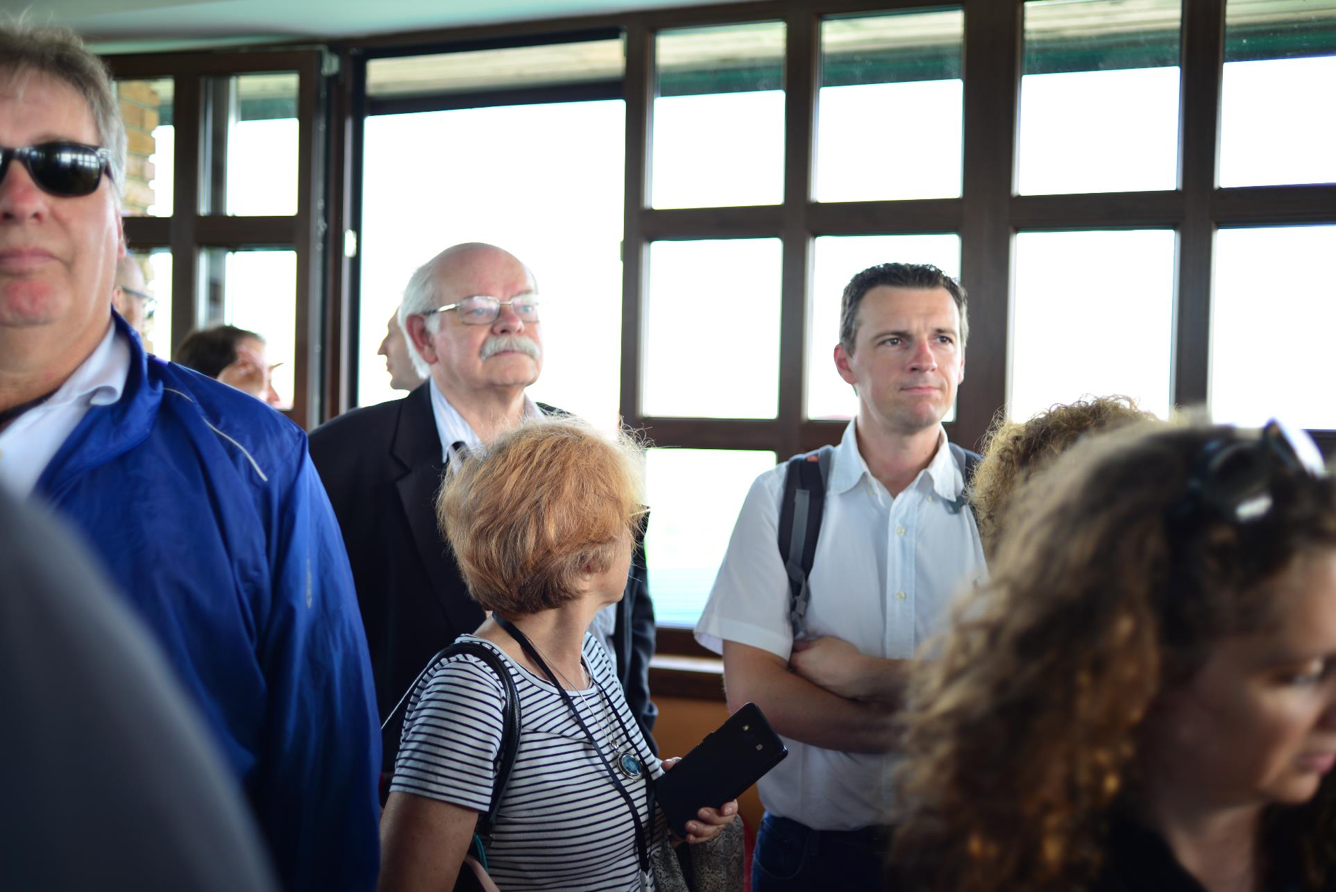 A group of people standing next to a window

Description automatically generated